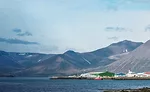 Small Town on Waterfront with Mountain Range and Sky Backdrop