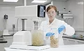 Female Scientist Scooping Ingredients Next to Silverson Lab Mixer