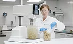 Female Scientist Scooping Ingredients Next to Silverson Lab Mixer